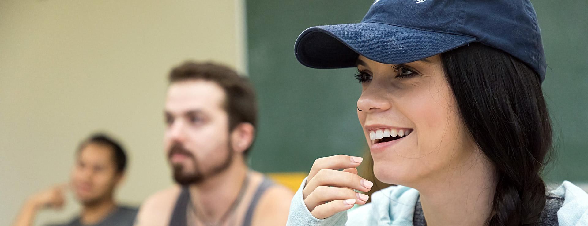 Female student smiling in class as other students look on