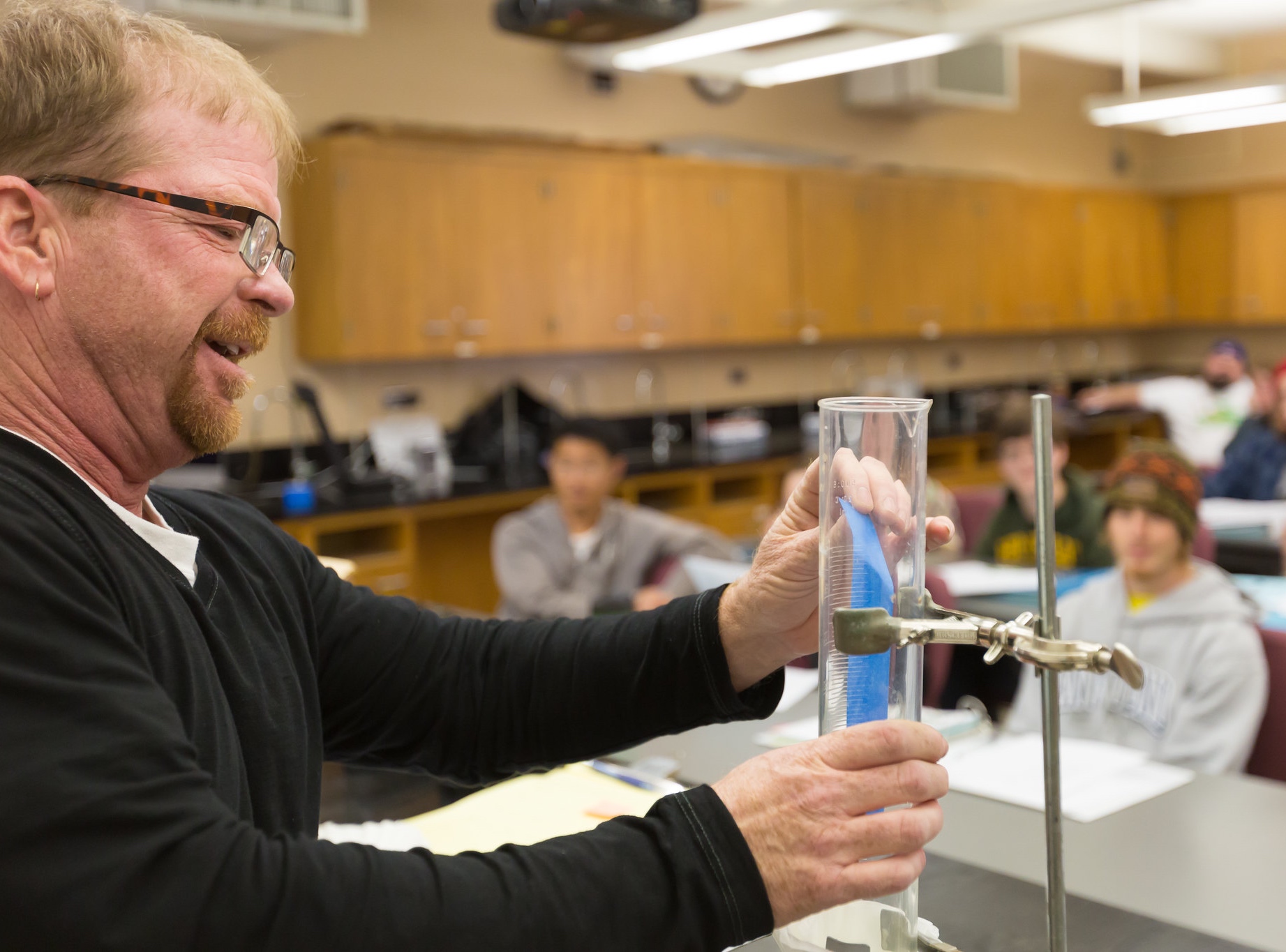 Professor doing experiment with large graduated cylinder.