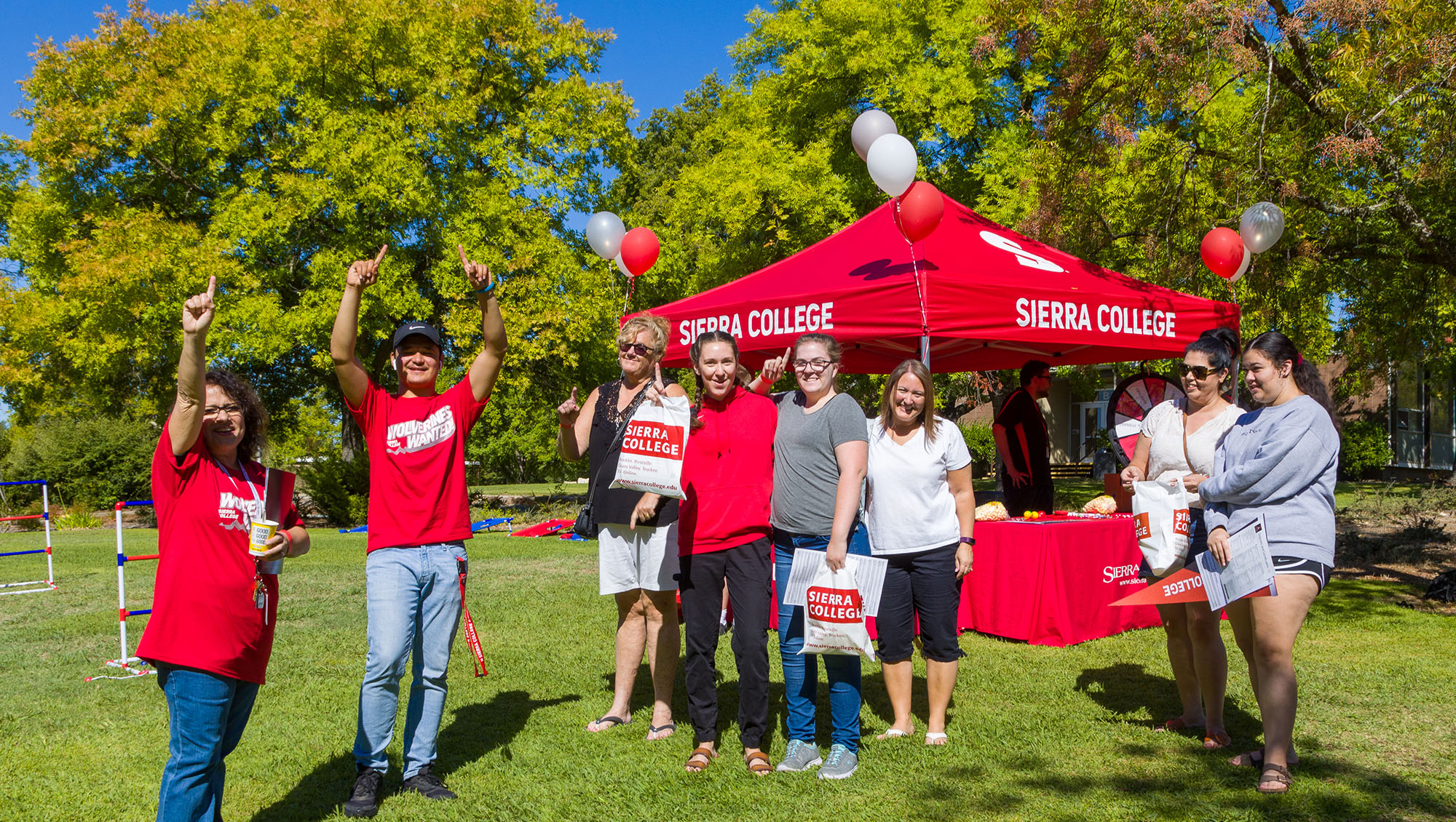 Red welcome tent with Sierra College staff cheering on prospective students and their families