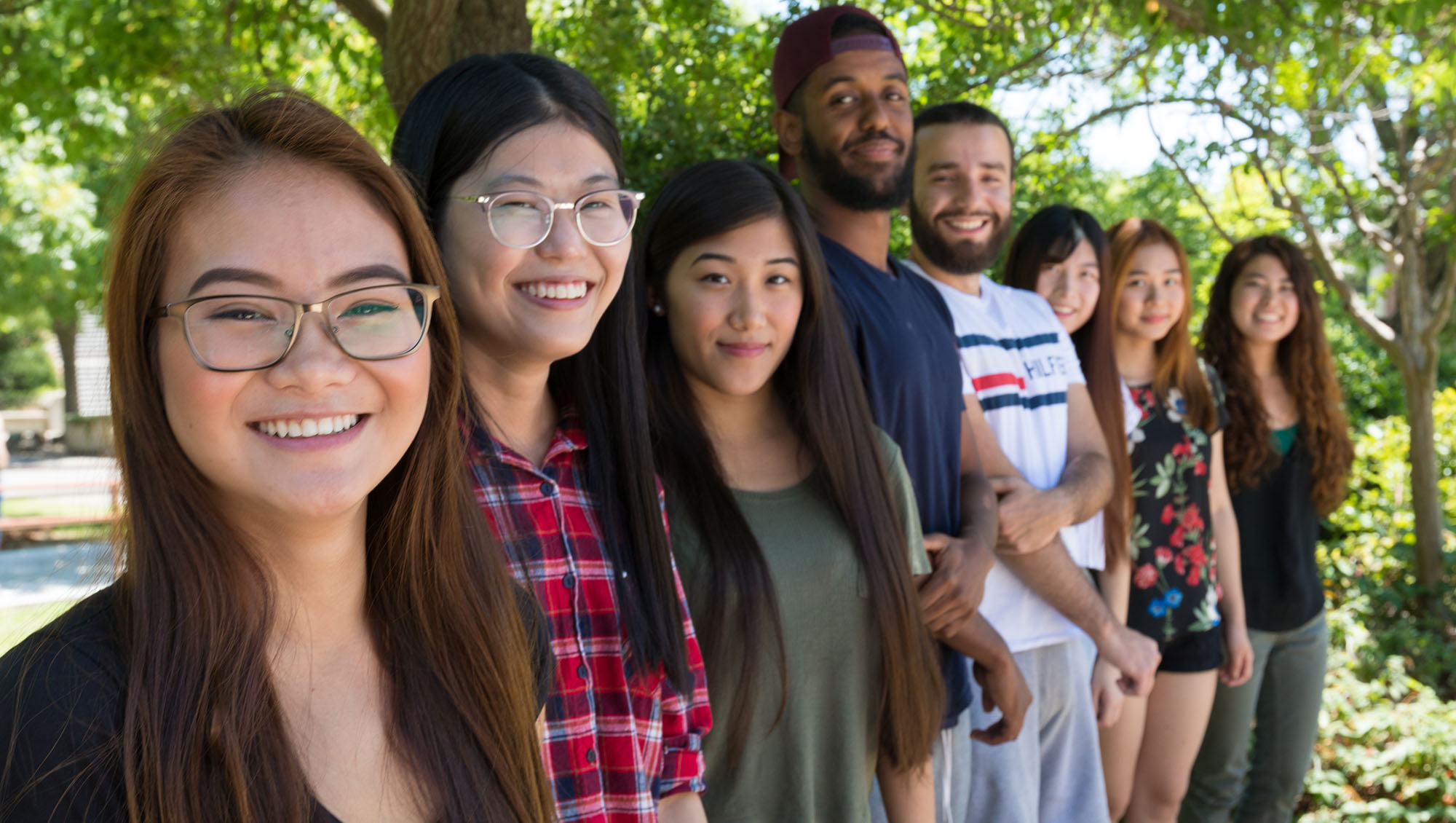 Diverse group of international students standing in a line with receding perspective.