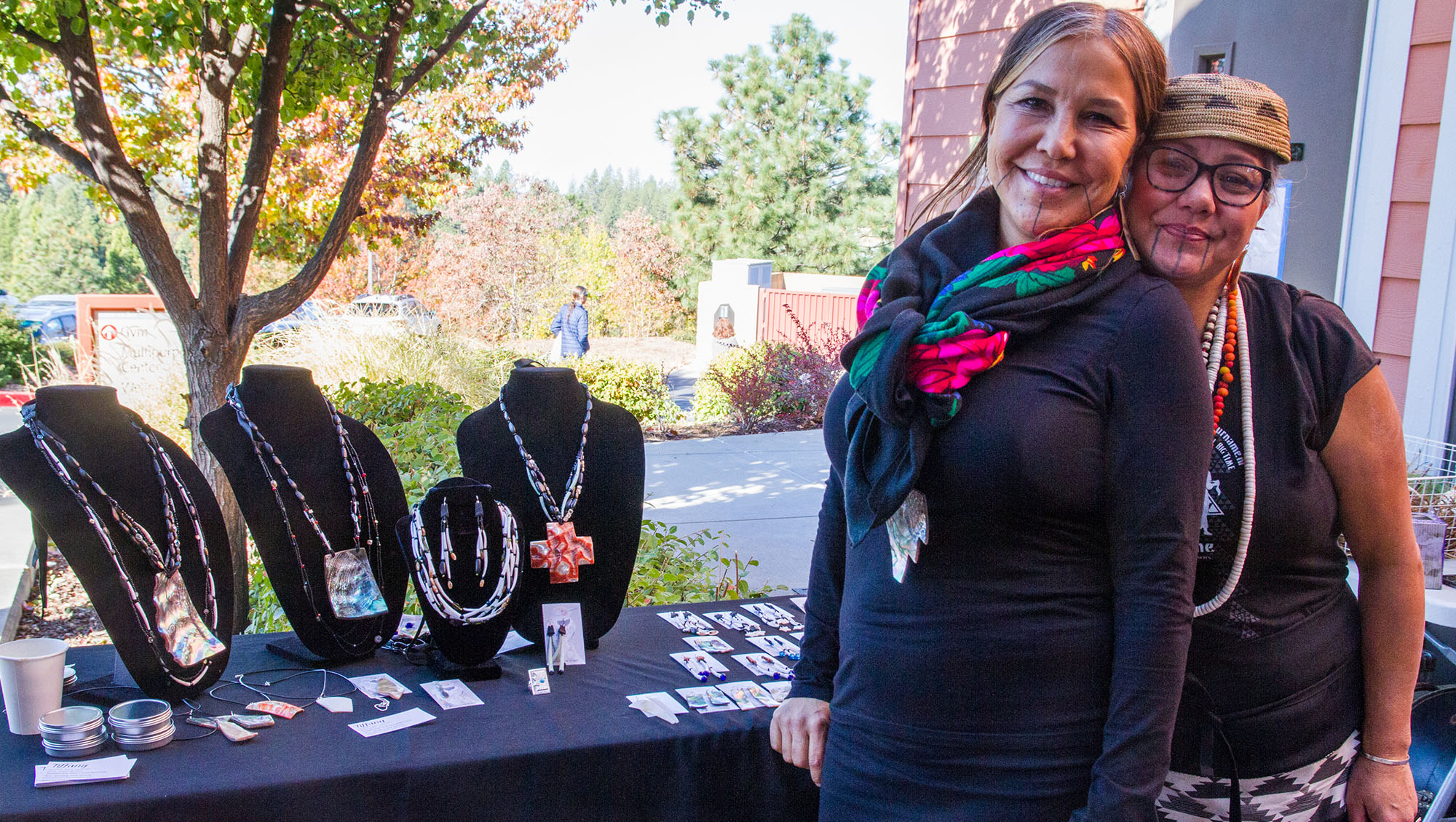 Two Nisenan Native American women selling traditional and contemporary jewelry including necklaces and earrings