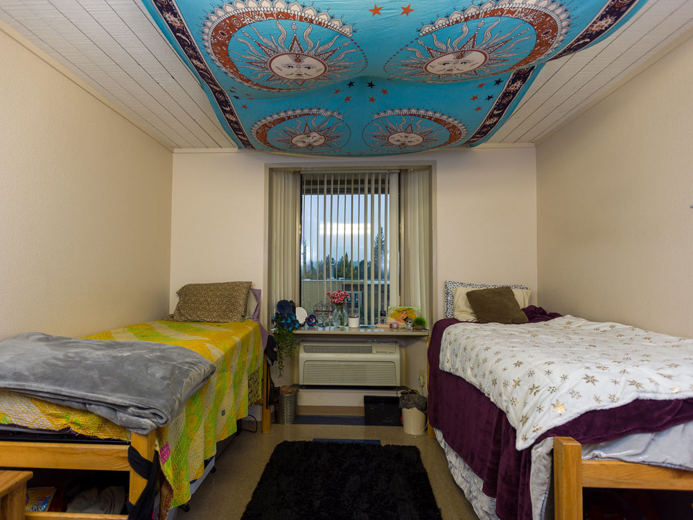 A shared dorm room with two beds and a window